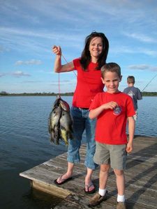 Woman and boy on dock with a stringer of Coppernose Bluegill. 